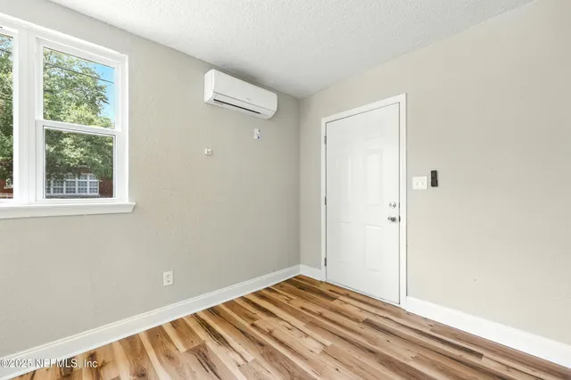 a view of an empty room with a window and wooden floor