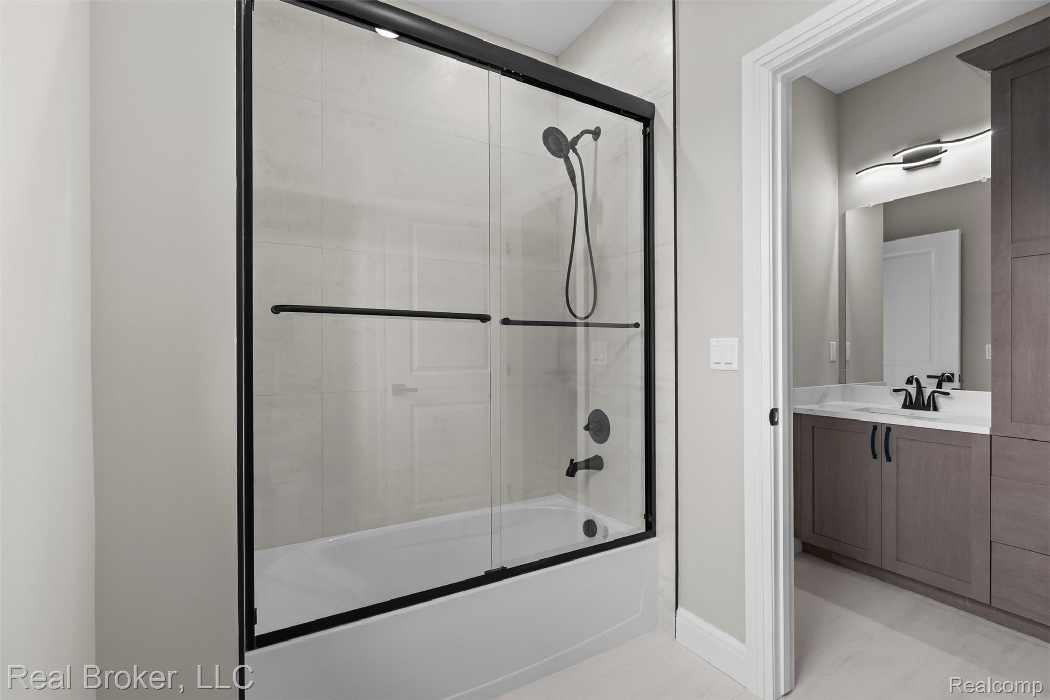 12114 22 Mile Road Utica, MI 48315 - Photo 46 of 70 White tiled shower with black-framed glass sliding doors and matte black fixtures