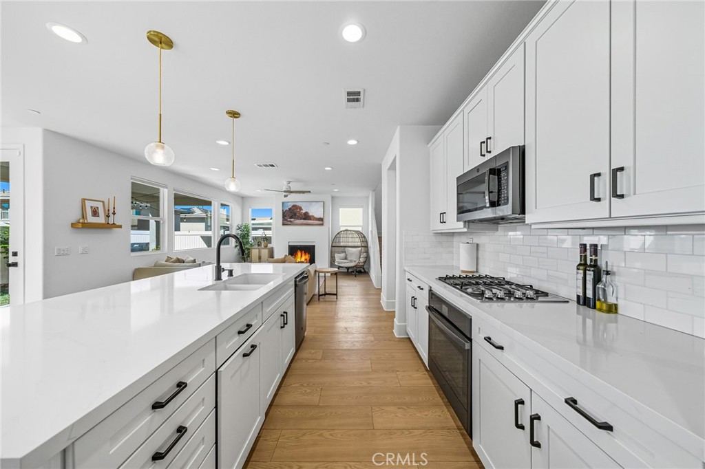 32017 Radiant Drive Temecula, CA 92591 - Photo 24 of 74 a large kitchen with stainless steel appliances granite countertop a stove a sink dishwasher and a microwave with wooden floor