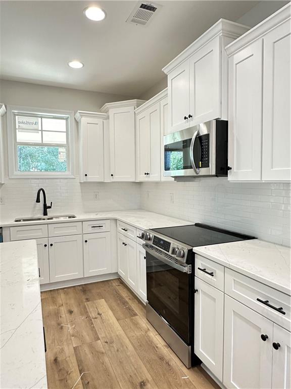 10 Lee Road Salem, AL 36874 - Photo 9 of 25 White shaker-style cabinetry with crown molding, stainless steel appliances, quartz countertops, white subway tile backsplash, and wood-finish flooring