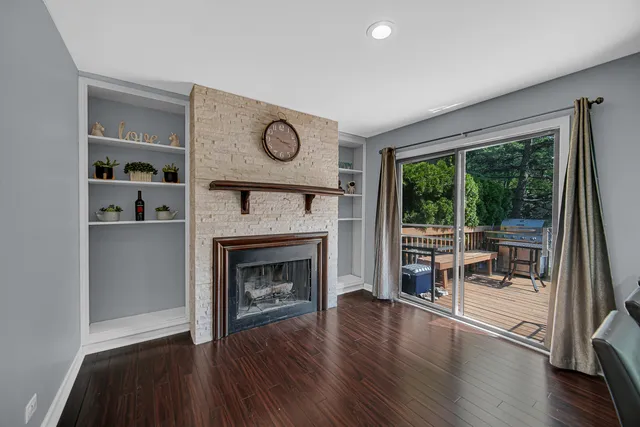 a view of a livingroom with furniture a fireplace wooden floor and a window
