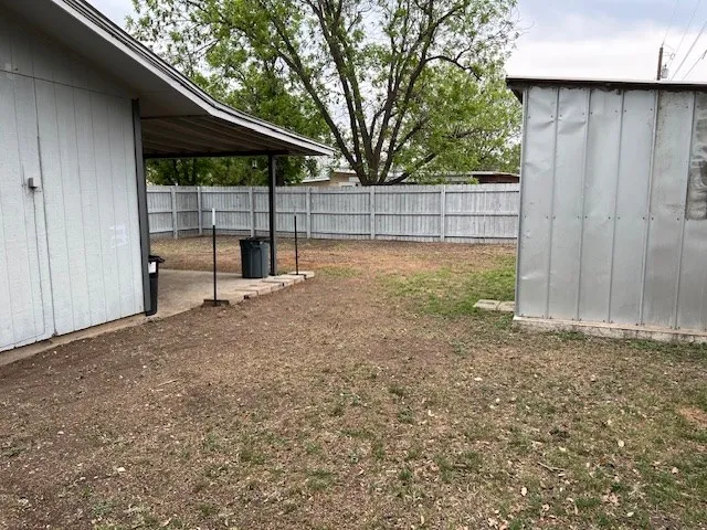 a view of backyard with table and chairs under an umbrella