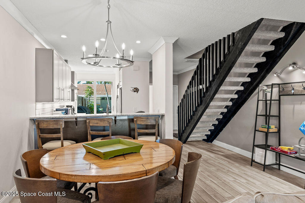 3044 South Hwy A1A, Unit 3C Melbourne Beach, FL 32951 - Photo 8 of 30 a dining room with furniture a chandelier and wooden floor
