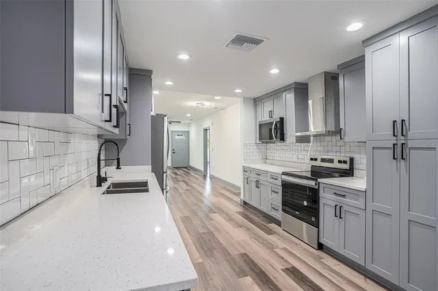 a kitchen with stainless steel appliances kitchen island granite countertop a stove a sink and a refrigerator with wooden floor