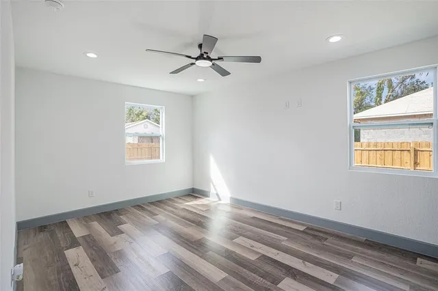 a view of empty room with wooden floor and fan
