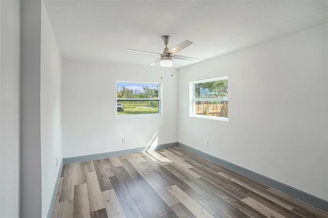 an empty room with a window and a ceiling fan