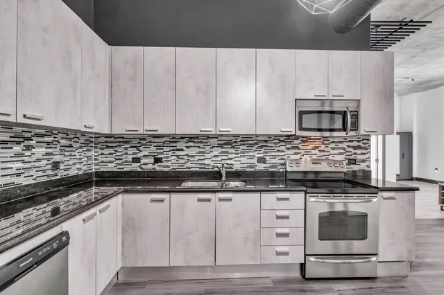 a kitchen with granite countertop a stove and white cabinets