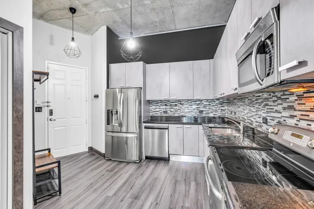 a kitchen with stainless steel appliances and wooden floor