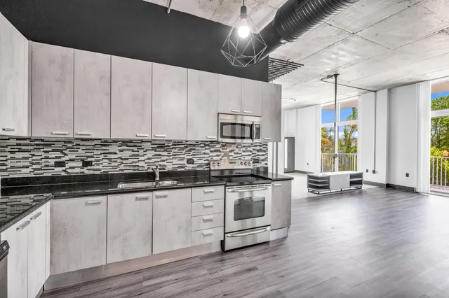 a kitchen with stainless steel appliances granite countertop a stove a sink and a microwave