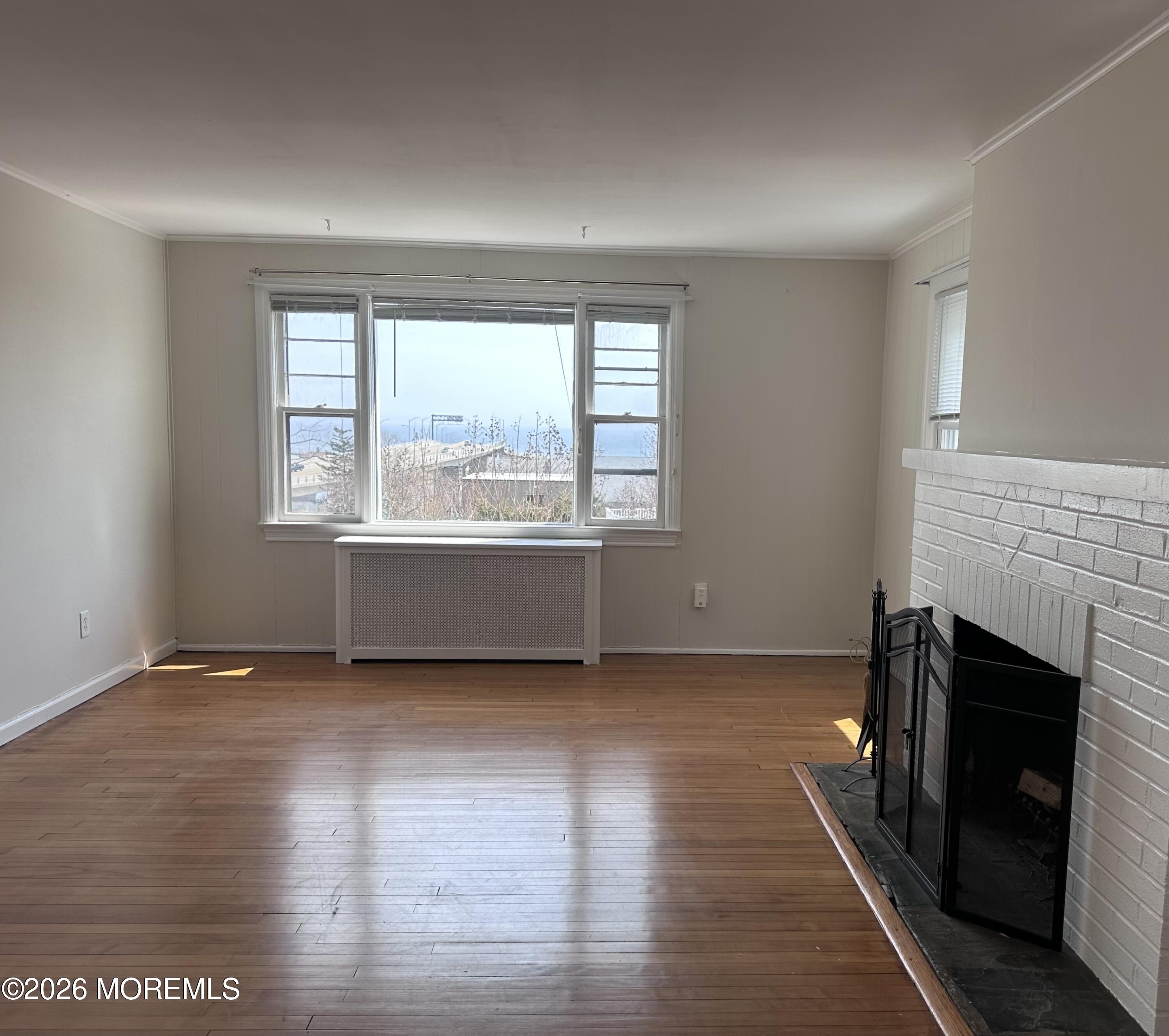 10 Ocean Street Highlands, NJ 07732 - Photo 2 of 15 an empty room with wooden floor fireplace and windows