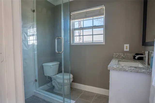 a bathroom with a granite countertop toilet a sink and a window
