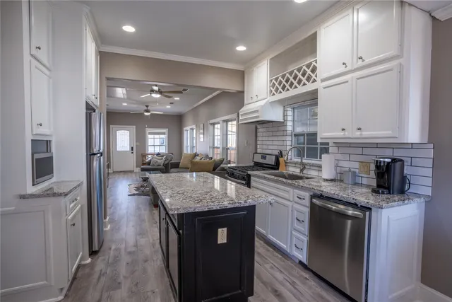 a kitchen with stainless steel appliances granite countertop a sink stove and cabinets