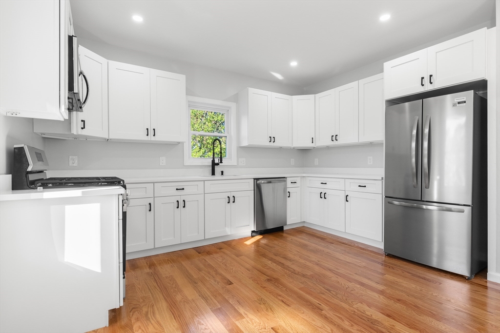 68 Middlebury Street Lawrence, MA 01841 - Photo 27 of 41 a kitchen with white cabinets stainless steel appliances and wooden floors