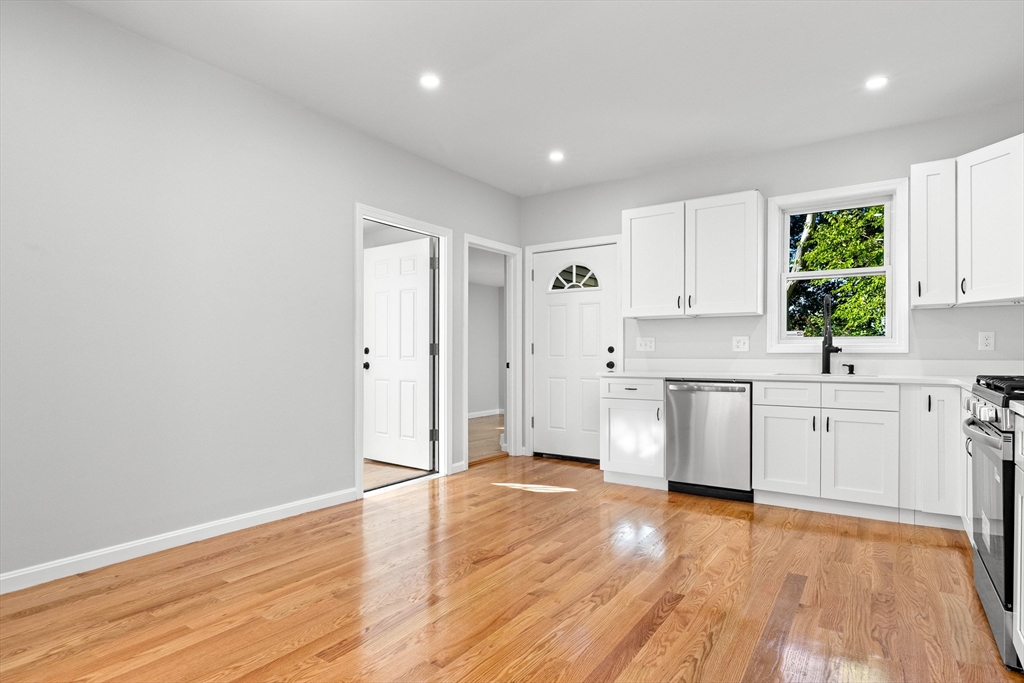 68 Middlebury Street Lawrence, MA 01841 - Photo 6 of 41 a kitchen with granite countertop a stove a sink and white cabinets with wooden floor