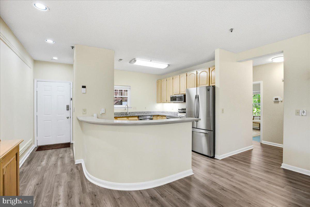 1126 Back Creek Loop, Unit 1126 Solomons, MD 20688 - Photo 9 of 47 a kitchen with stainless steel appliances a refrigerator and wooden floor