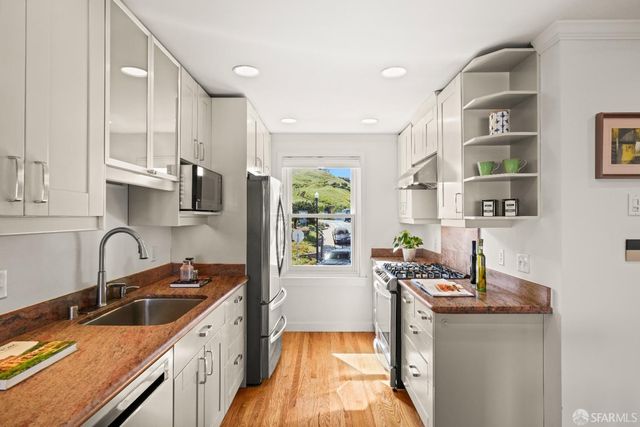 a kitchen with granite countertop a sink stainless steel appliances and cabinets