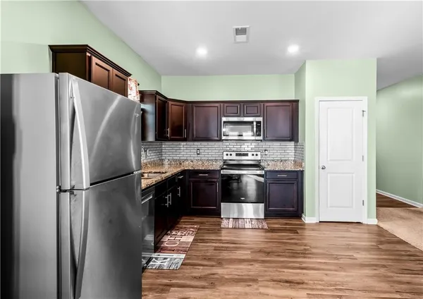 a kitchen with stainless steel appliances granite countertop a refrigerator a stove a sink and a microwave