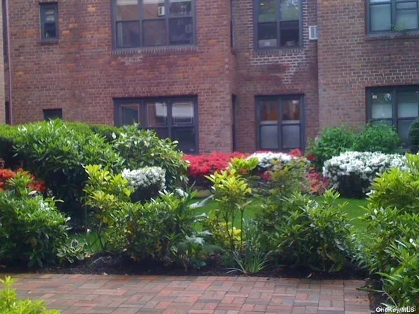 a view of a brick house with a flower garden
