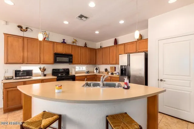 a kitchen with stainless steel appliances a sink a stove a refrigerator cabinets and wooden floor