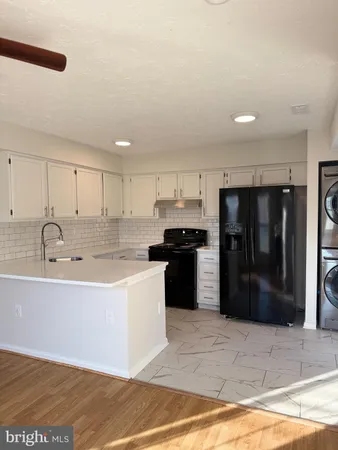 a large kitchen with stainless steel appliances kitchen island granite countertop a refrigerator and a sink