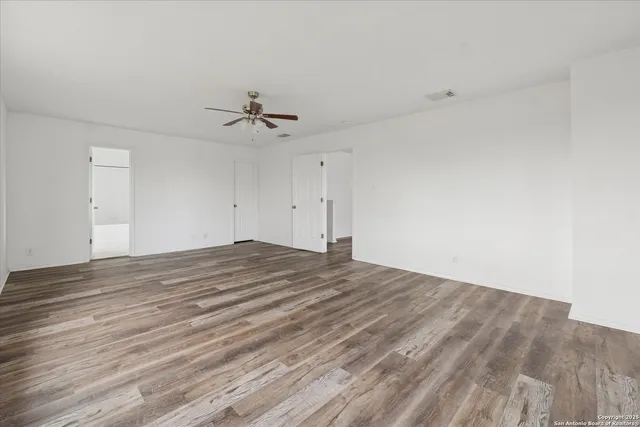 an empty room with wooden floor and ceiling fan
