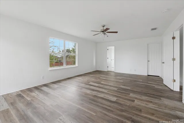 a view of empty room with wooden floor and fan