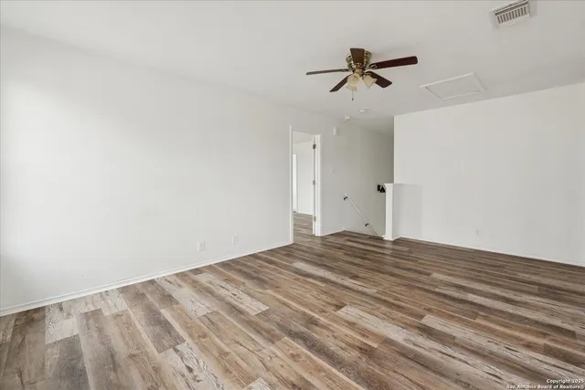 a view of empty room with wooden floor and ceiling fan