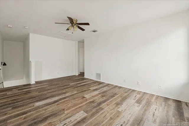 a view of a room with wooden floor and ceiling fan