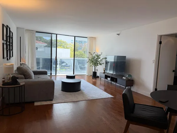 a living room with furniture a flat screen tv and a large window