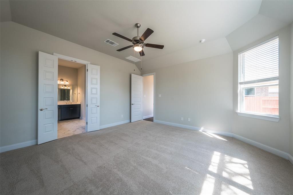 113 Old Trinity Way Georgetown, TX 78628 - Photo 12 of 27 Unfurnished bedroom featuring vaulted ceiling, light carpet, a ceiling fan, and connected bathroom