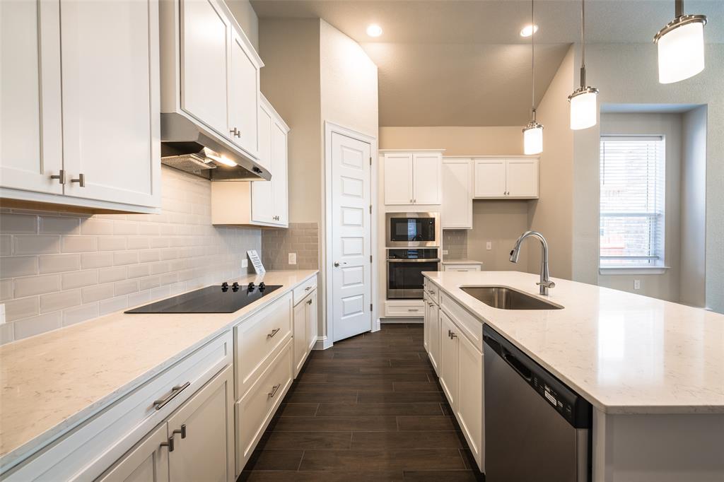 113 Old Trinity Way Georgetown, TX 78628 - Photo 4 of 27 Kitchen with stainless steel appliances, white cabinetry, light stone counters, and an island with sink