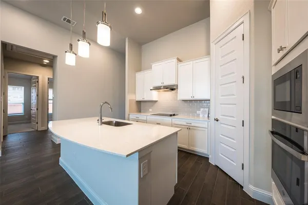 a kitchen with a sink dishwasher stove and white cabinets with wooden floor