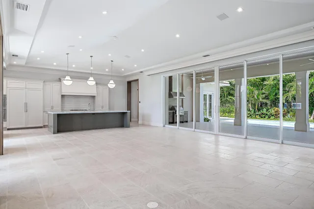a view of an empty room with a kitchen and window