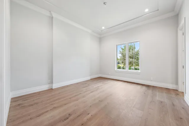 an empty room with wooden floor and window