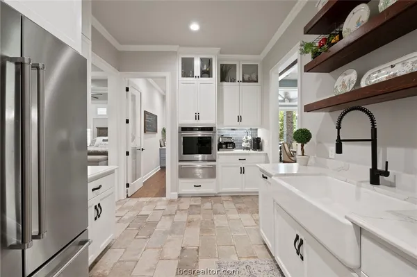 a large white kitchen with stainless steel appliances and a refrigerator