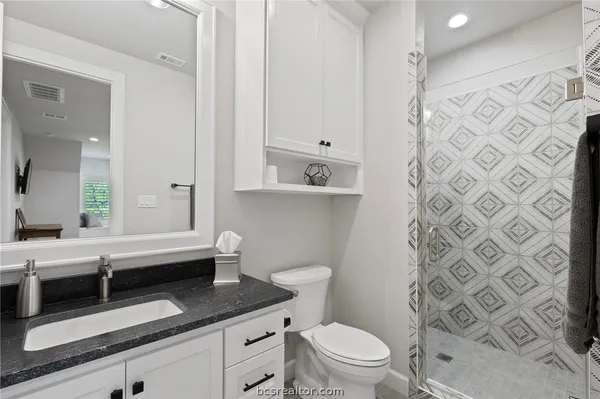 a bathroom with a granite countertop sink a toilet and a shower