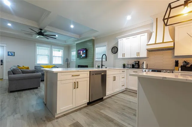a kitchen with white cabinets a sink dishwasher and a stove with wooden floor