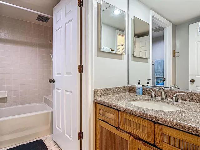 a bathroom with a granite countertop sink and a mirror a bathtub