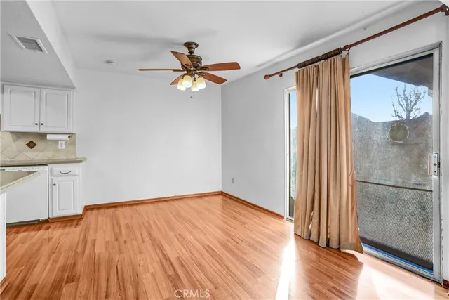 a view of a livingroom with wooden floor a ceiling fan and windows