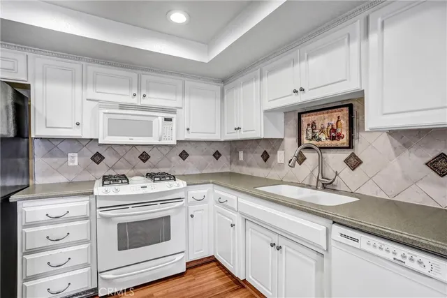 a kitchen with granite countertop white cabinets and white appliances