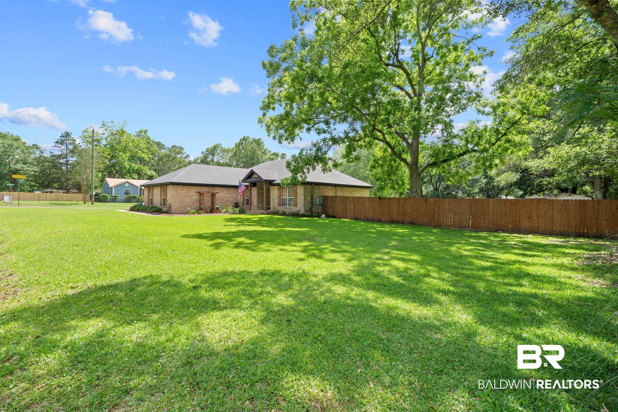 5936 Lundy Road Theodore, AL 36582 - Photo 29 of 32 Expansive front lawn leading to a single-story brick exterior home with a dark shingled roof