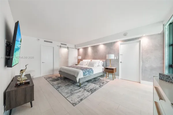 a spacious bedroom with a bed and a flat screen television