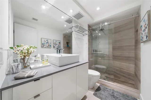 a bathroom with a granite countertop sink a toilet a mirror and shower