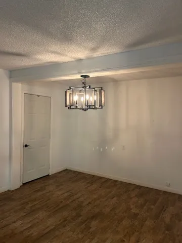 a view of an empty room with wooden floor and chandelier