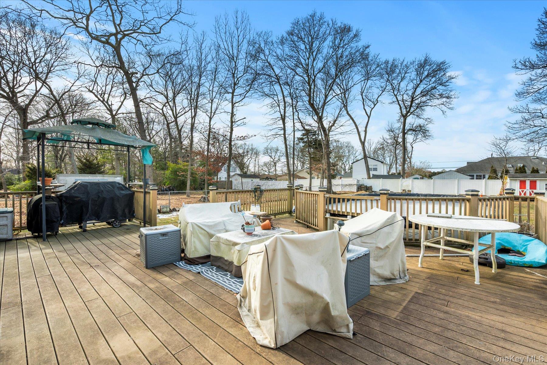 214 Pipe Stave Hollow Road Mount Sinai, NY 11766 - Photo 22 of 25 a view of a patio with table and chairs couches with wooden floor and fence