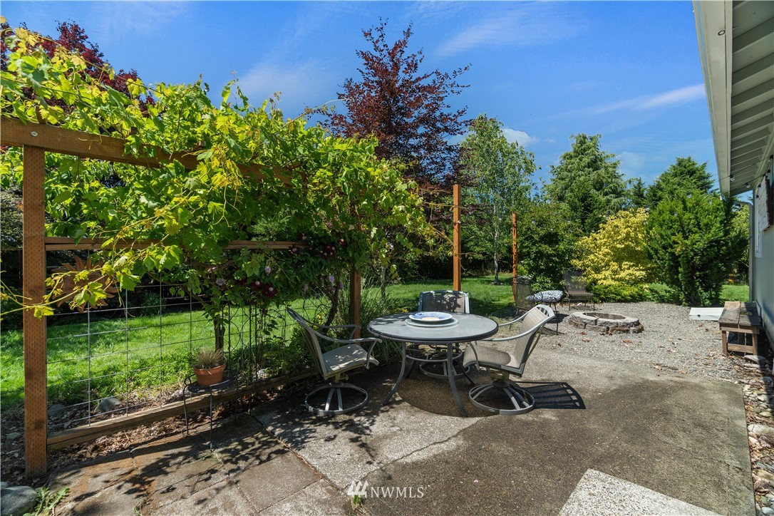 18135 Tamara Lane Southwest Rochester, WA 98579 - Photo 16 of 20 a view of a backyard with table and chairs potted plants and large tree