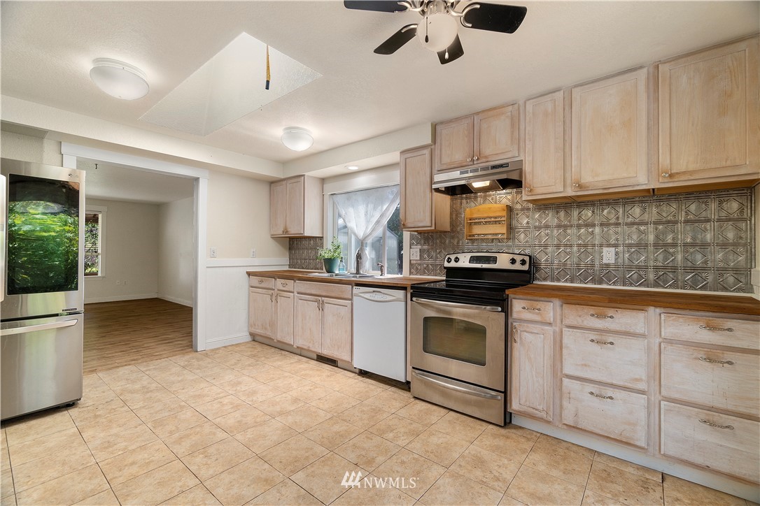 18135 Tamara Lane Southwest Rochester, WA 98579 - Photo 7 of 20 a kitchen with granite countertop a stove a sink and a refrigerator