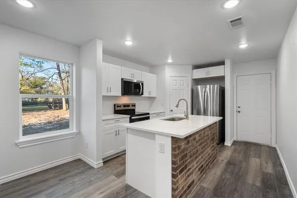 a kitchen with stainless steel appliances a sink a stove a refrigerator and cabinets