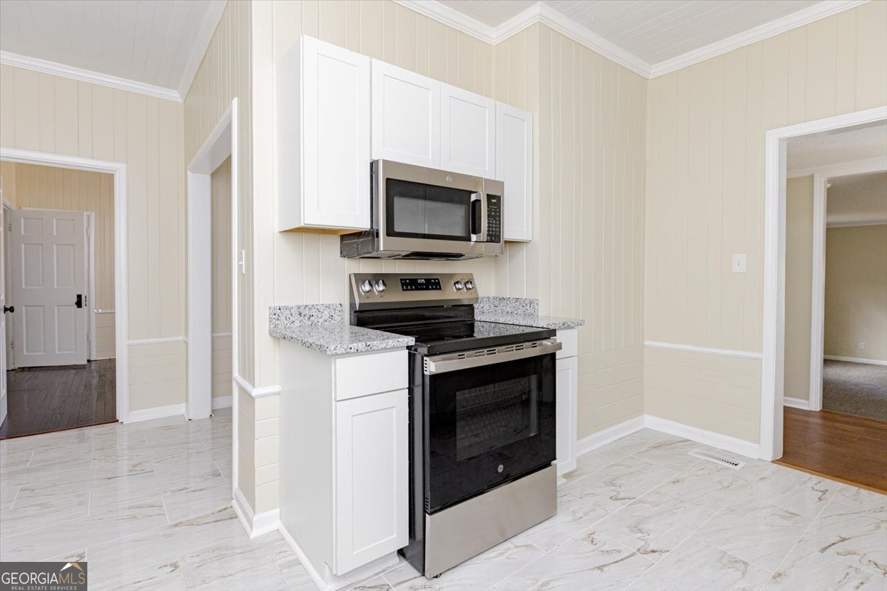 1205 Swift Street Perry, GA 31069 - Photo 23 of 63 a kitchen with stainless steel appliances granite countertop a stove a microwave and a refrigerator