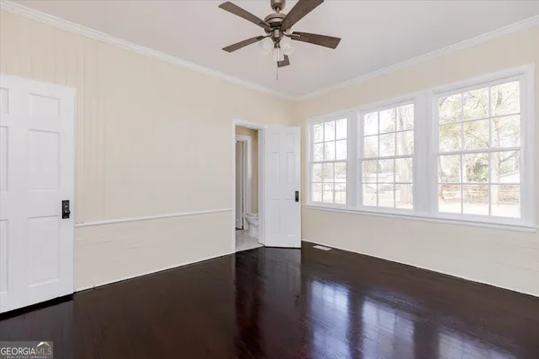 a view of empty room with wooden floor and fan